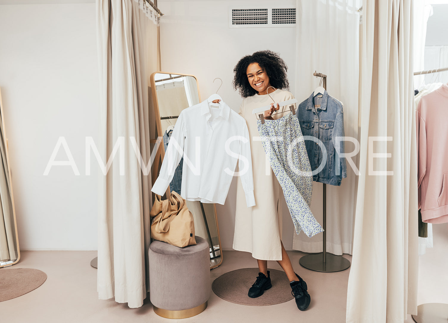 Happy woman standing with clothes in fitting room