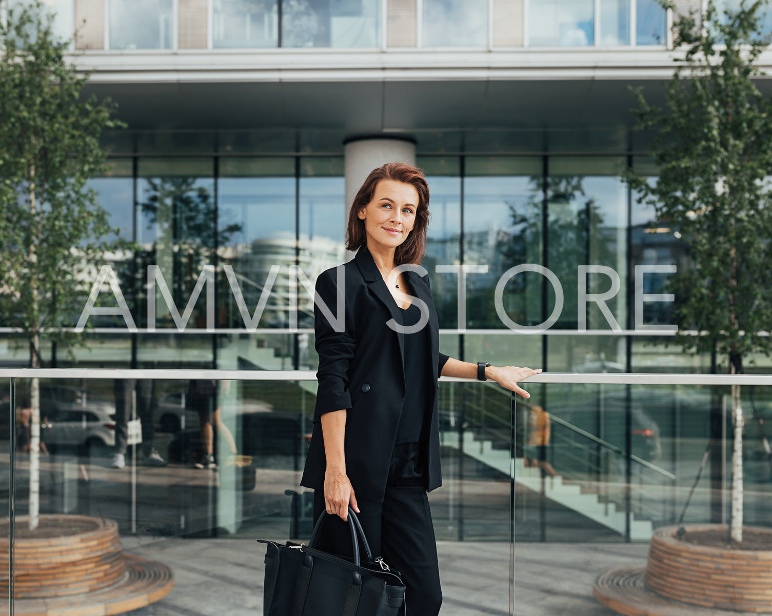 Side view of a confident middle-aged businesswoman with a bag standing against an office building