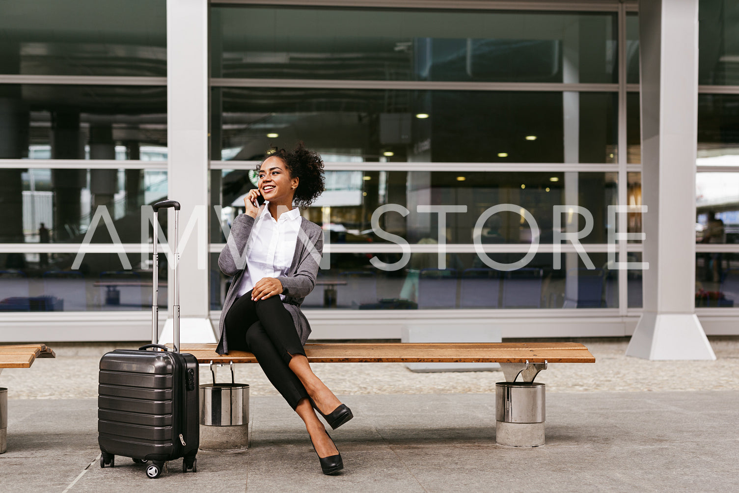 Young businesswoman sitting on a bench and talking on smartphone at airport terminal	