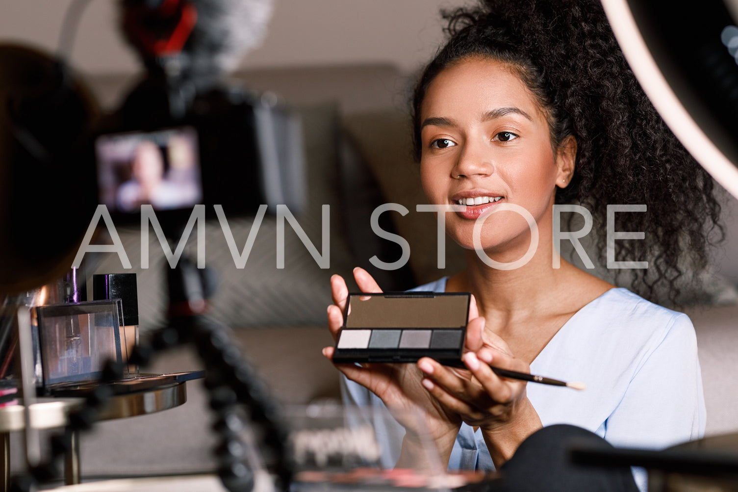 Young influencer making makeup tutorial while sitting in front of a camera