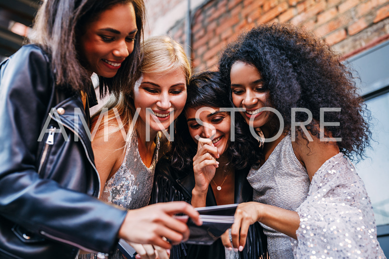 Four smiling women choosing instant photographs outdoors	