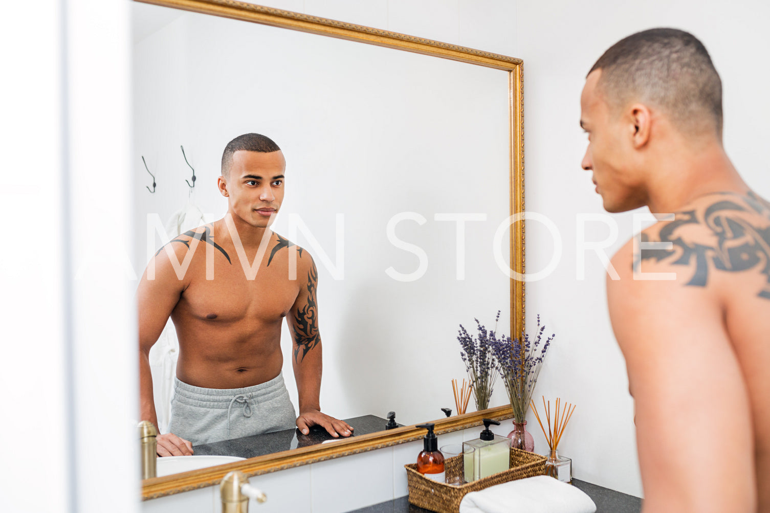 Bare-chested man examining his face in a mirror	