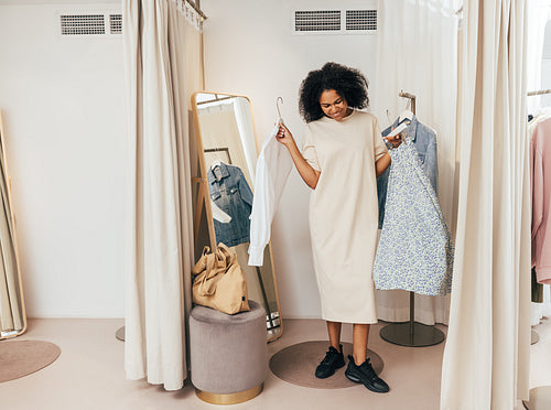 Young stylish woman standing in dressing room showing clothes she choosing