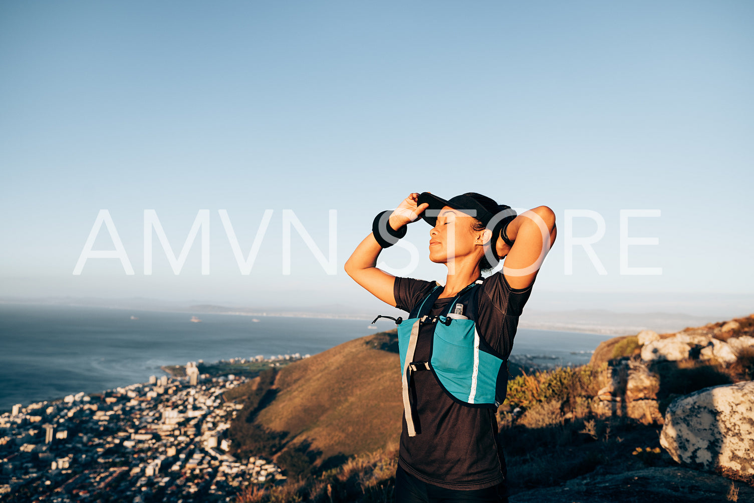 Woman hiker adjusting cap with closed eyes. Female trail runner feeling taking rest during a hike.