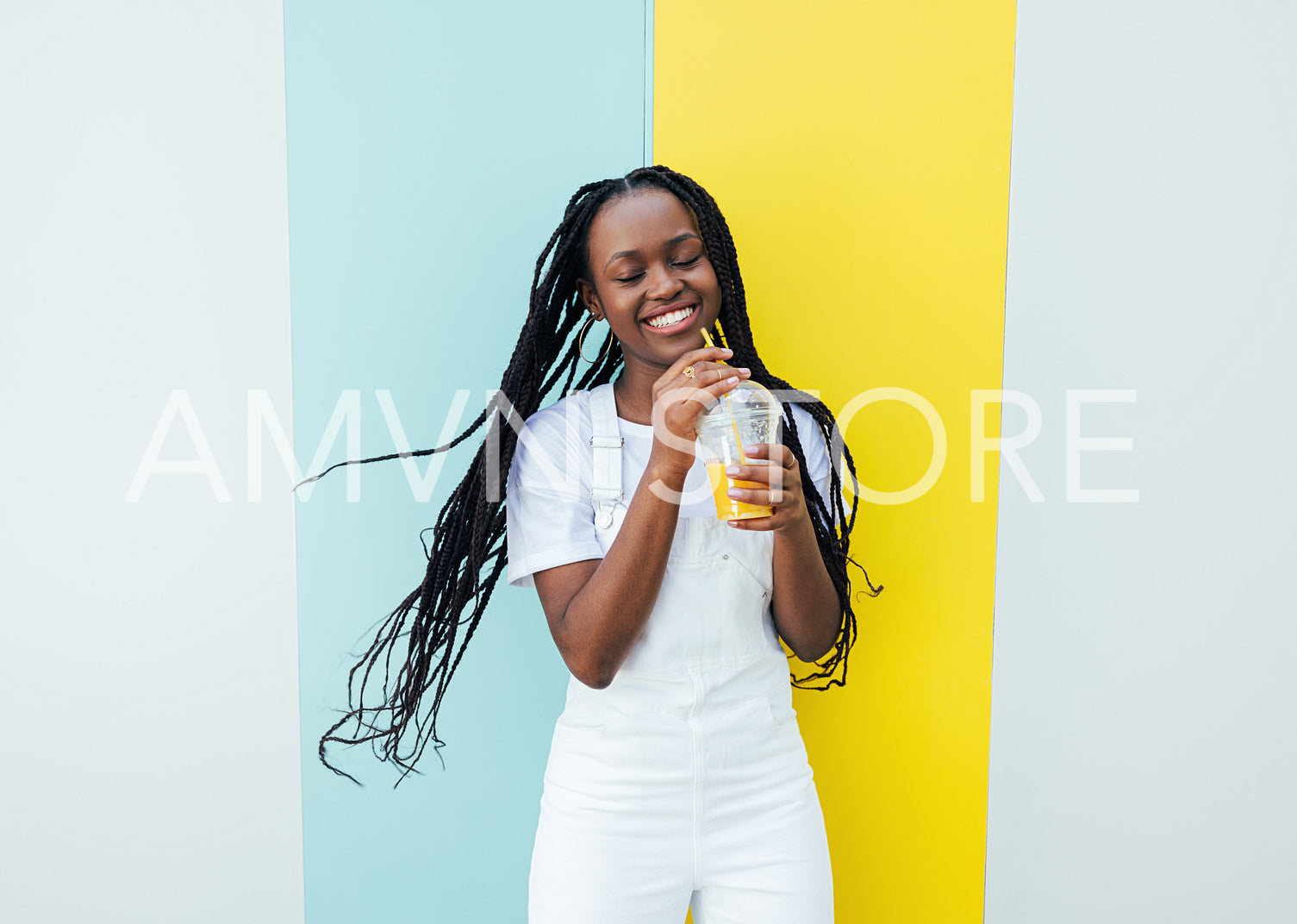 Happy girl in white clothes holding a cocktail and having fun while standing outdoors