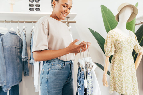 Woman working in a clothing shop. Young boutique owner holding hangers.