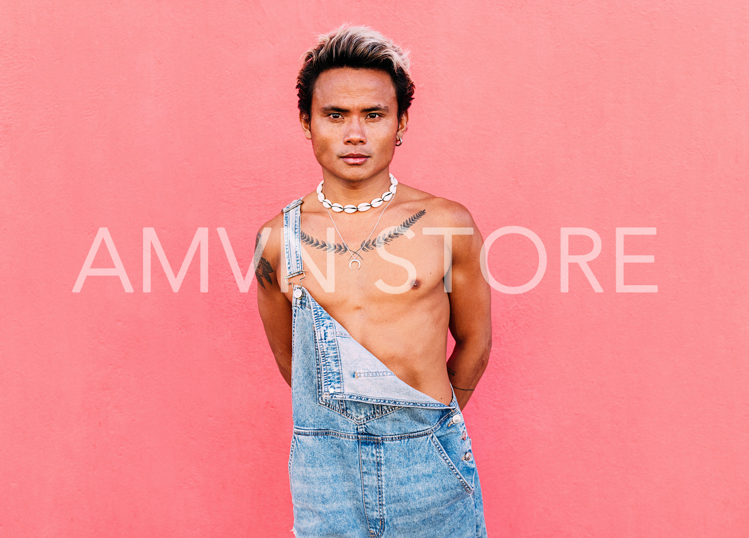 Portrait of a young handsome guy with bare chest looking at camera at pink wall