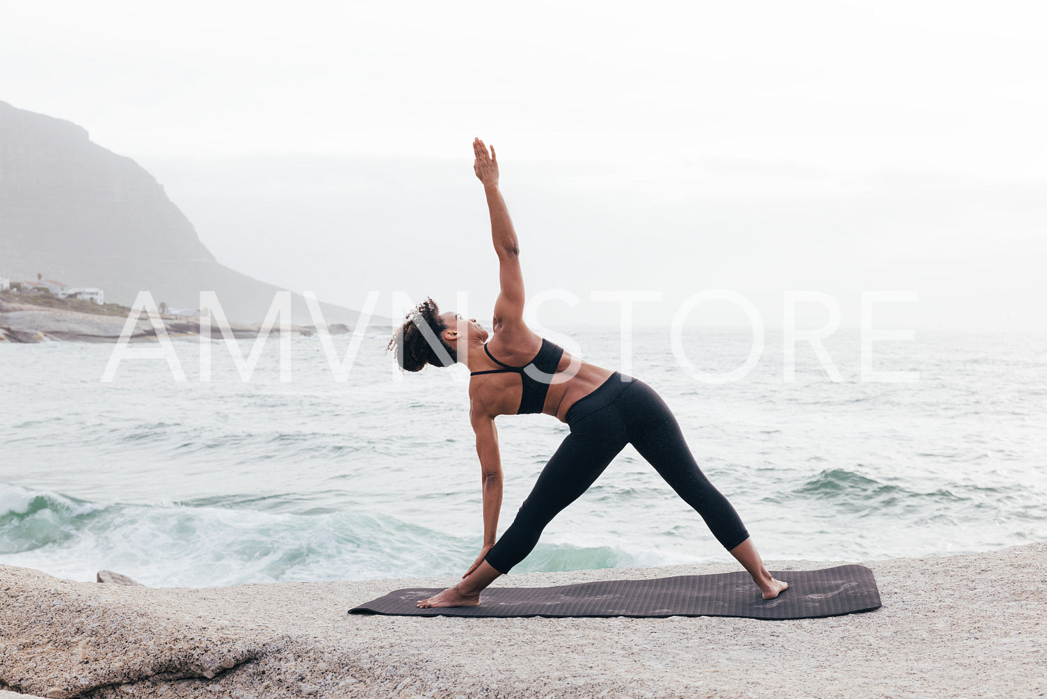 Slim female in sportswear practicing Trikonasana pose at beach