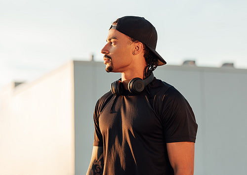 Young male athlete in cap relaxing during outdoor exercises