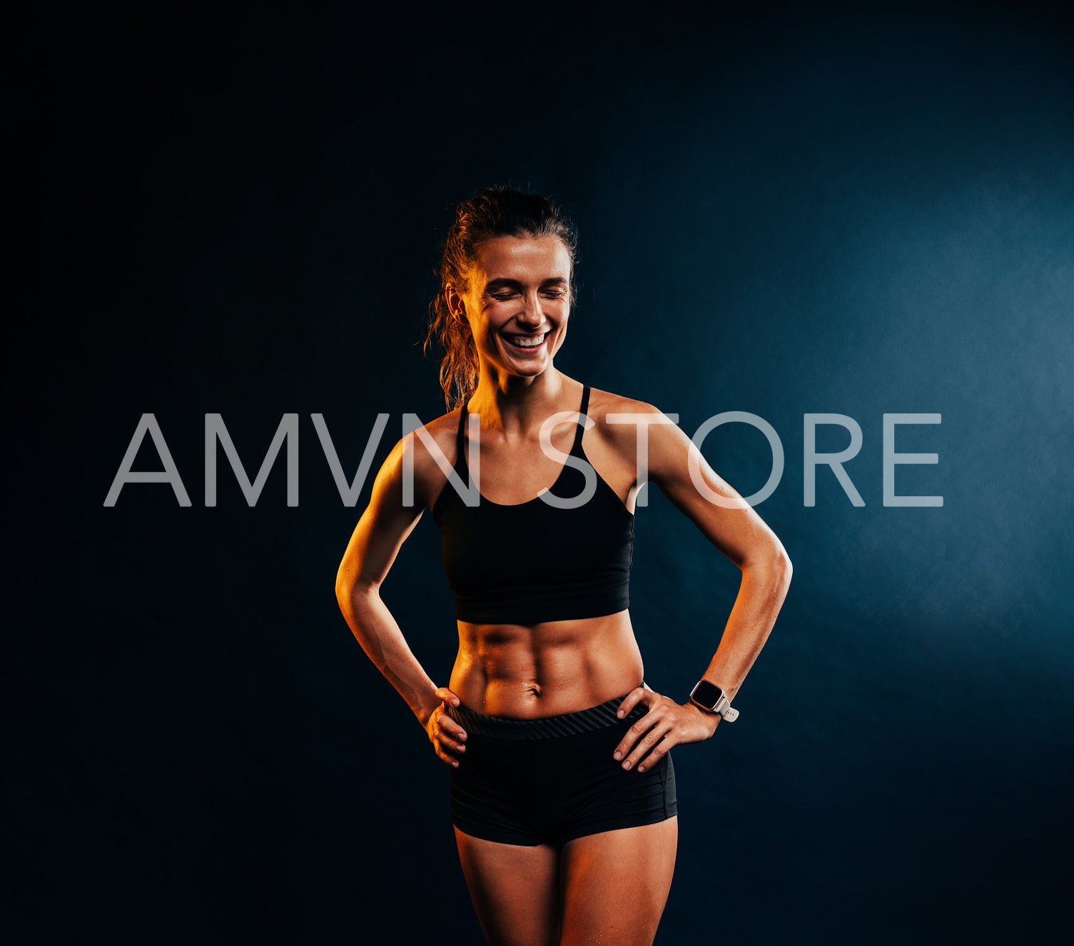 Portrait of young cheerful muscular woman in sportswear posing against black background