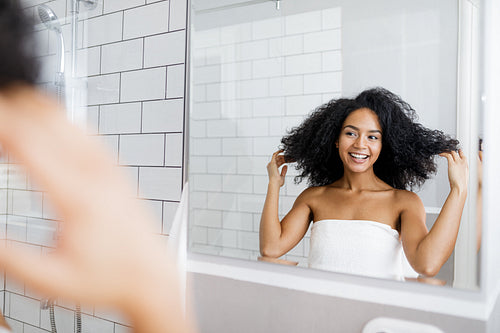 Young woman taking deciding on a hairstyle in front of a mirror