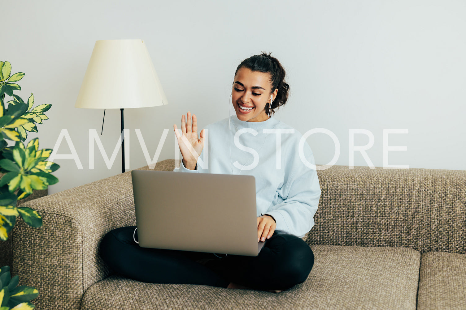 Smiling woman sitting on sofa in living room making gestures on a video call	