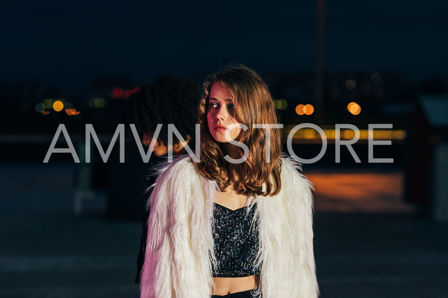 Young stylish woman looking away while standing on roof at night	