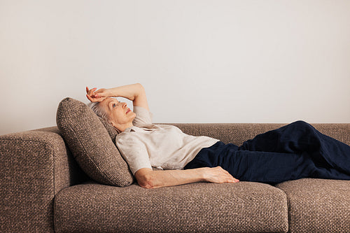 Tired aged woman lying on a bed. Senior female feels sick.