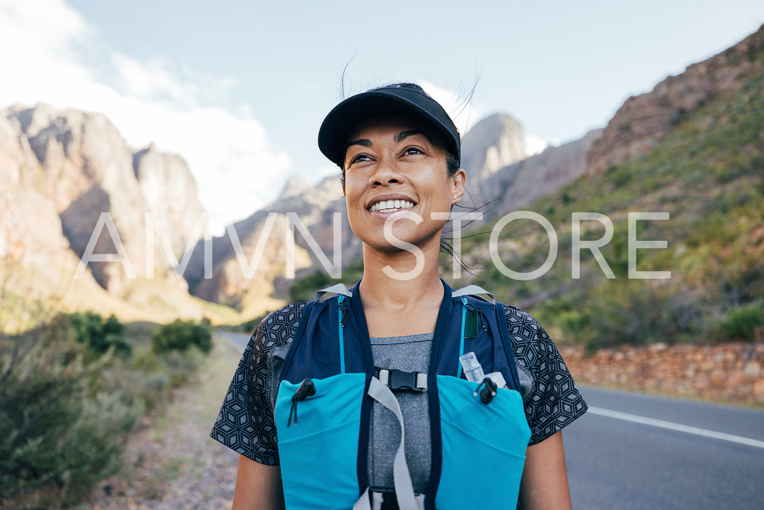 Portrait of a beautiful female hiker in cap. Woman in hiking attire staning in valley.