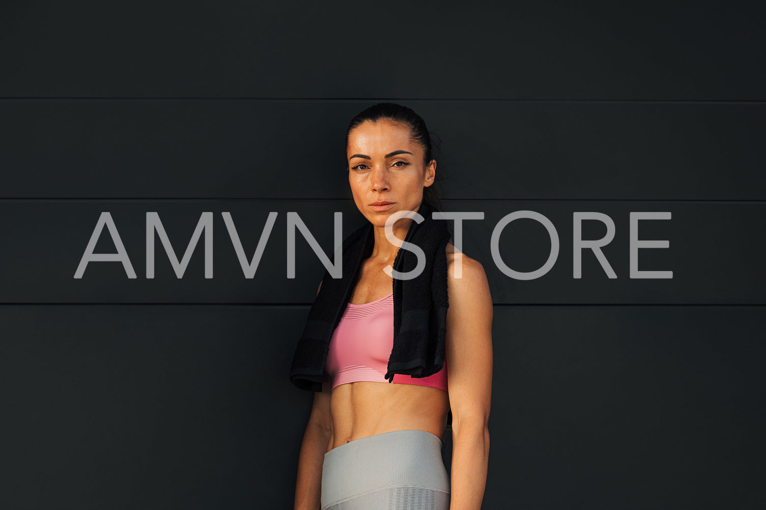 Woman athlete standing at black wall and looking at camera