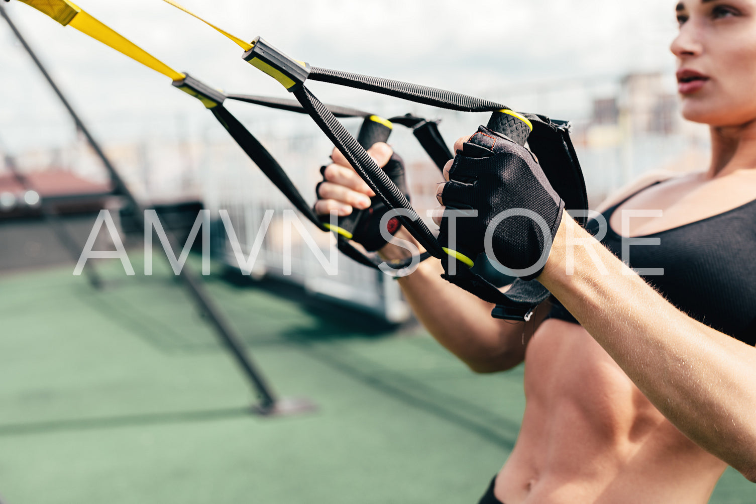 Sporty young woman doing exercises with suspension straps on roof terrace	
