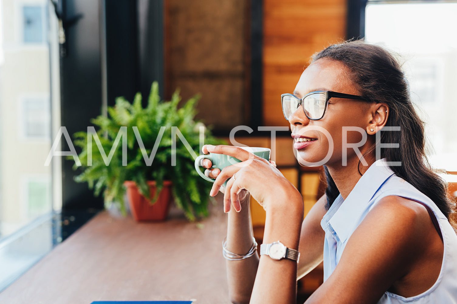 Woman sitting at cafe and looking away thinking with cup of coffee in hand	