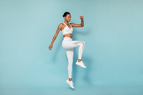 Young woman in sports wear warming up before training in studio