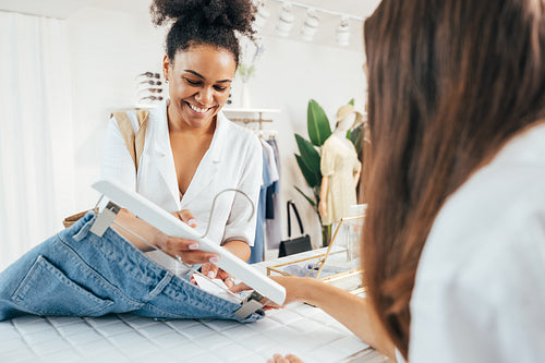 Unrecognizable saleswoman helping with size on a tag to the buyer at the counter