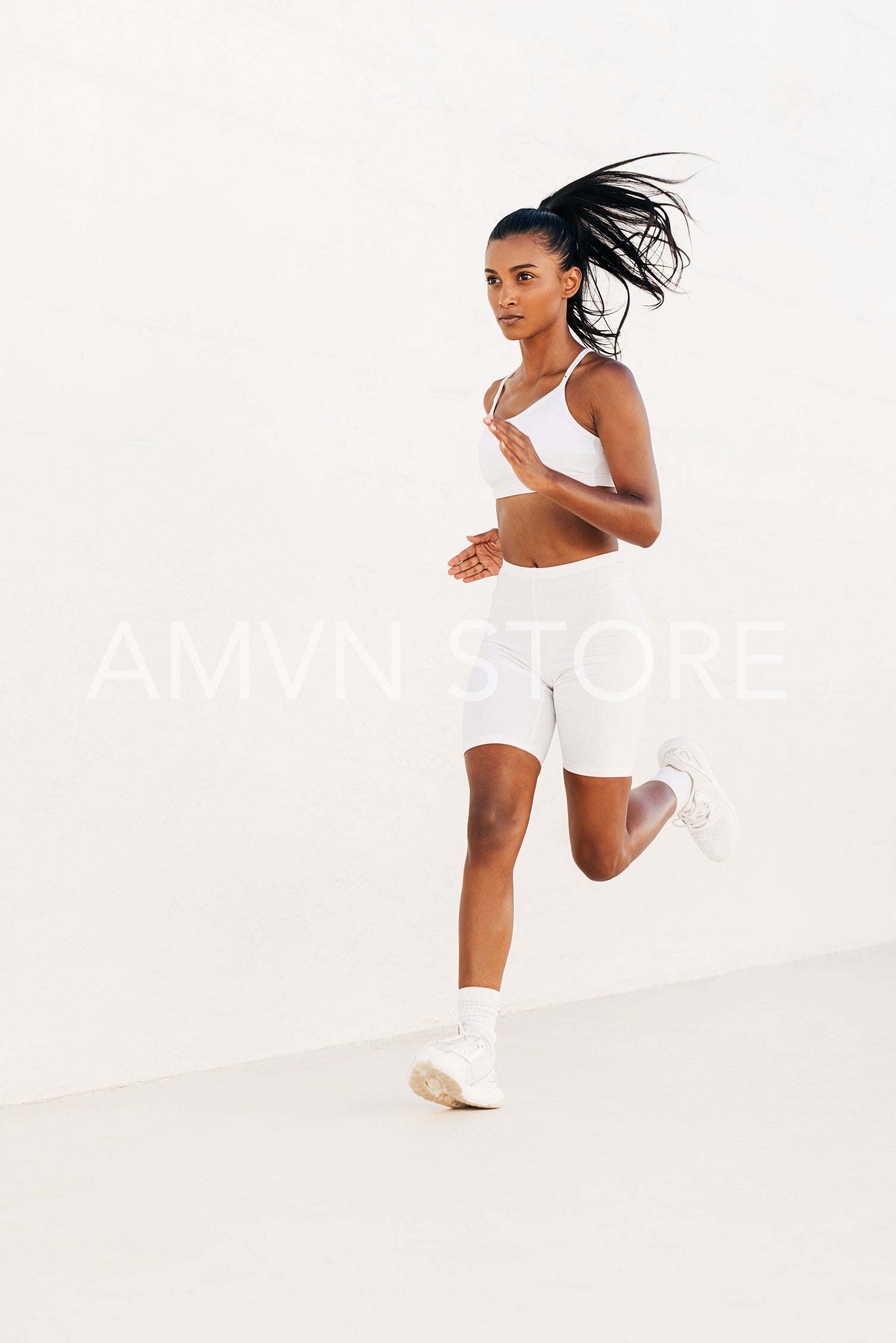 Fit female in white fitness attire jogging outdoors. Full length of a young woman sprinting.