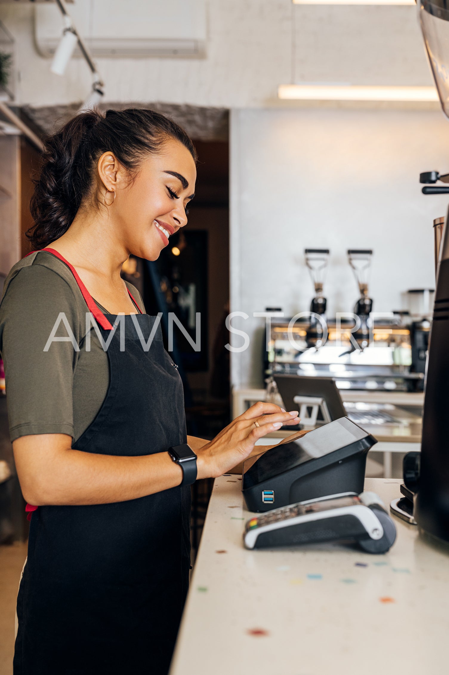 Side view of female waitress using cashbox computer in cafe. Woman touching a display of a electronic cash register.