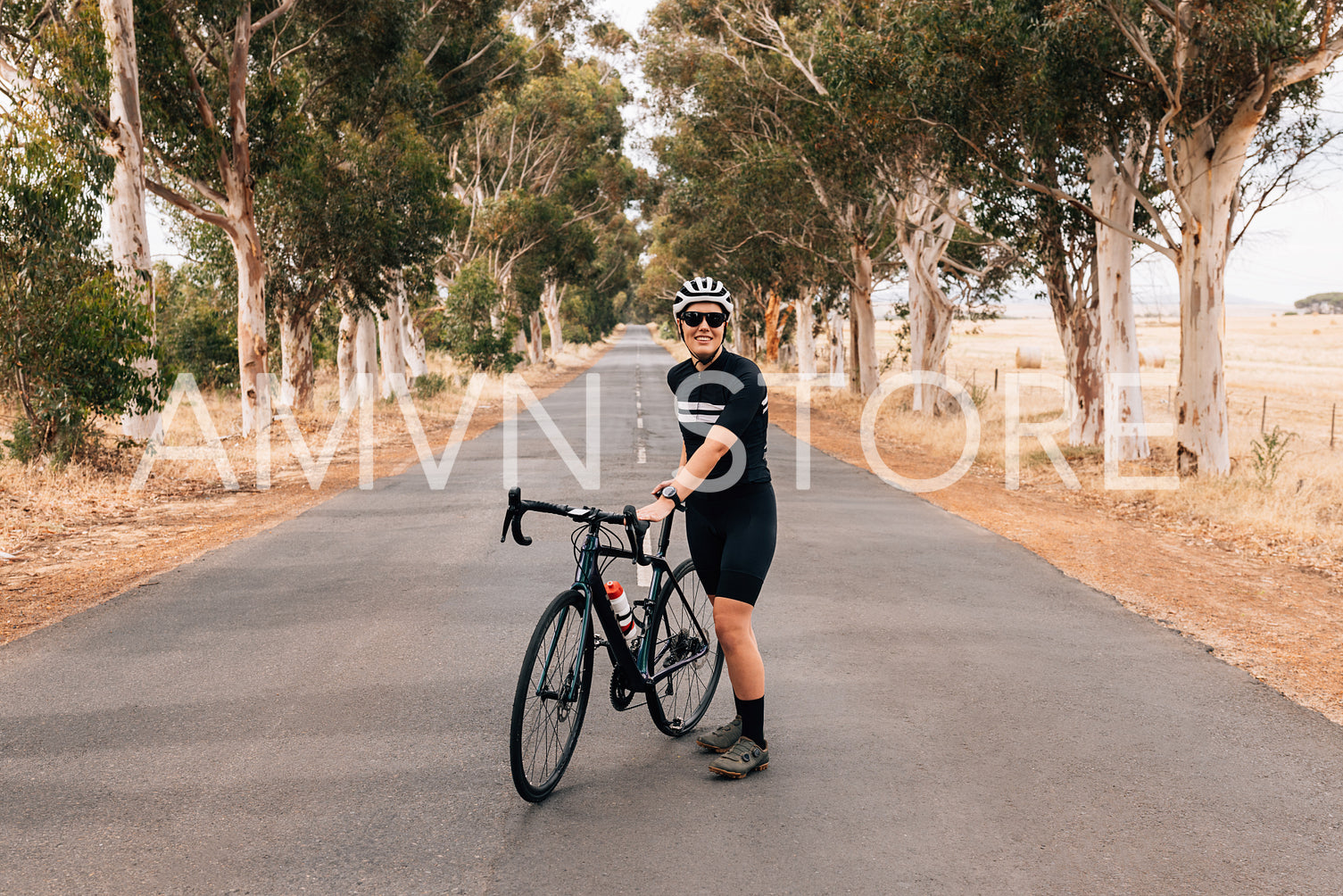 Woman cyclist taking rest standing of the center of the empty road 