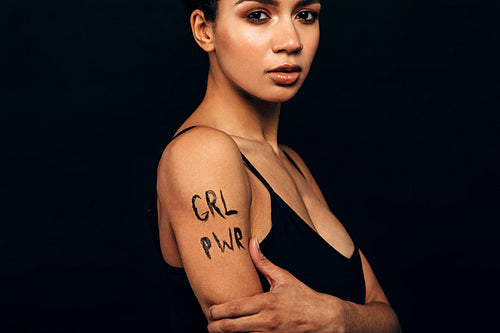 Portrait of a young serious woman posing over black background