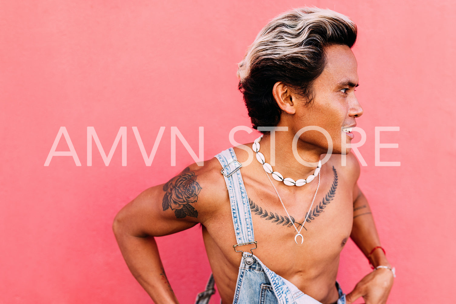 Close up of young male in denim clothing standing at pink wall l