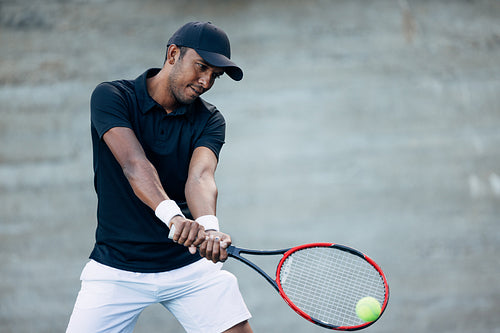 Confident tennis player hitting serve while playing outdoors