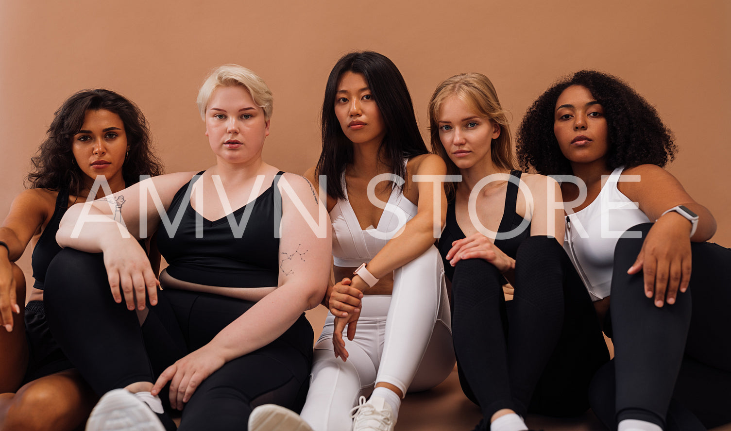 Five diverse women in sportswear sitting together and looking at the camera