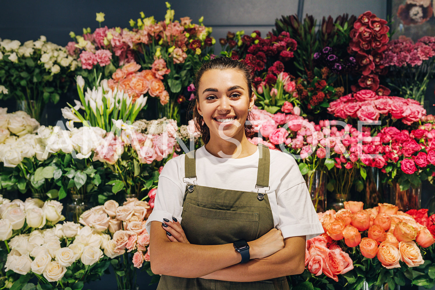 Woman florist standing in flower shop. Female florist in apron standing with her arms crossed.	