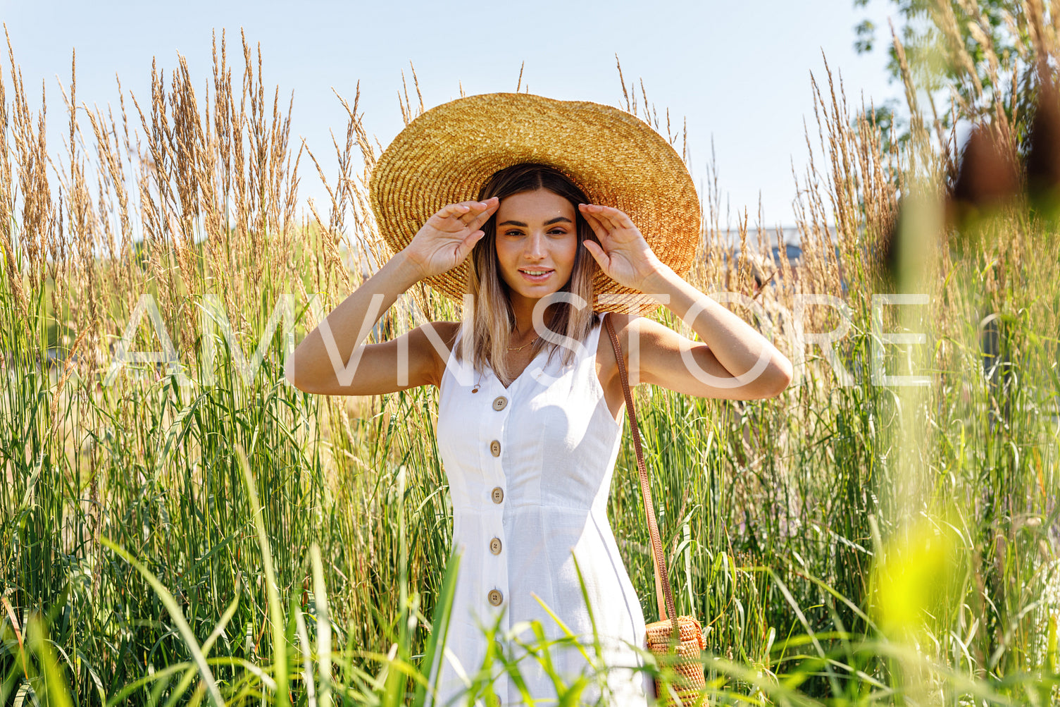 Beautiful stylish woman posing on the field and looking at camera	