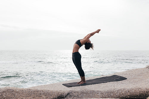 Woman in Standing Backbend Pose by ocean