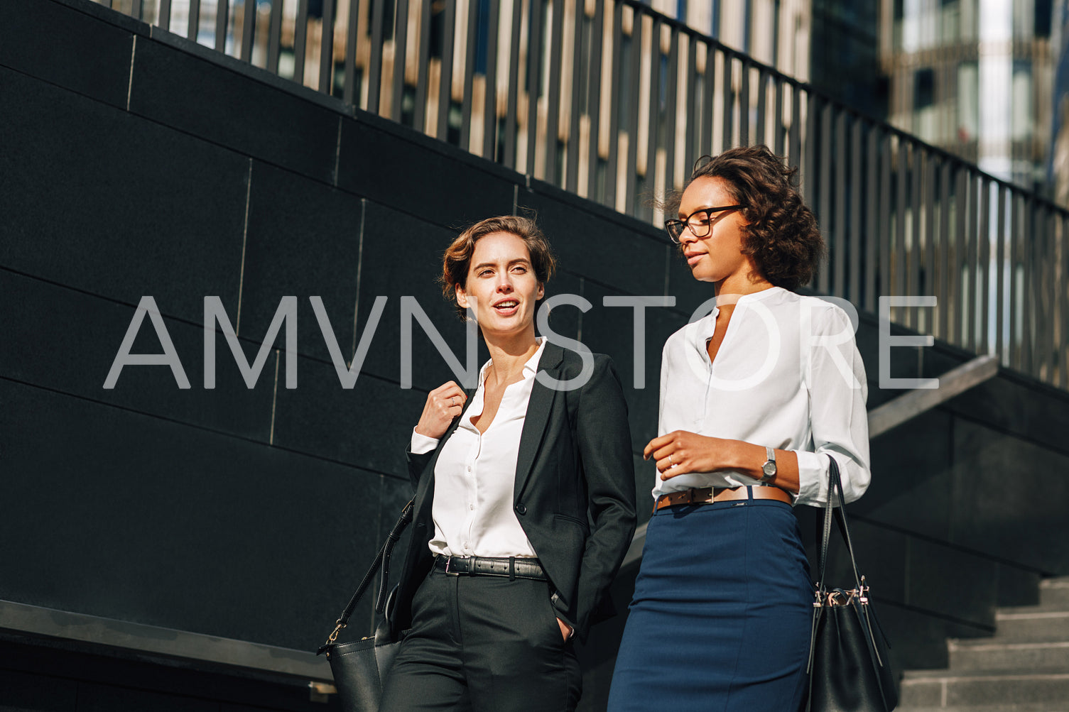 Two coworkers stepping down on the stairs and talking	