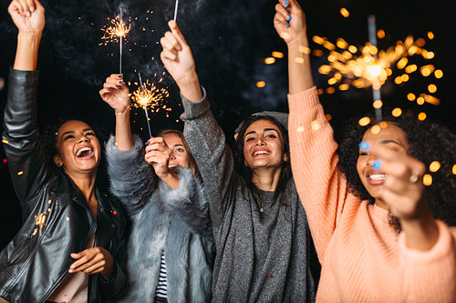 Group of young female friends having fun, raised hands up with sparklers