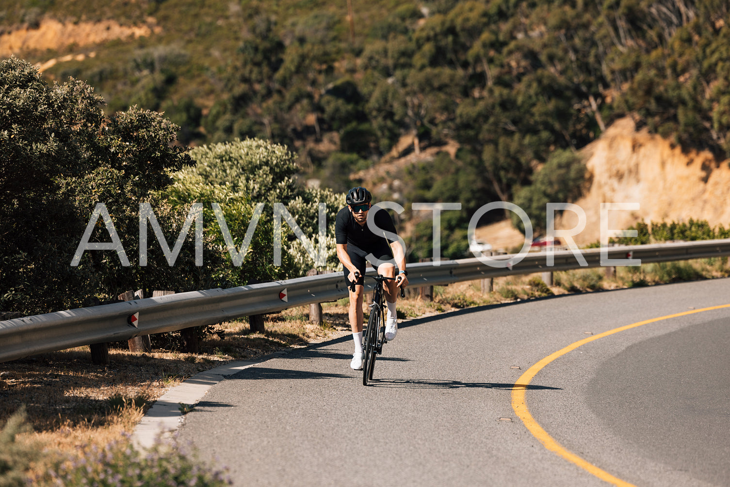 Male cyclist riding a bike on an empty mountain road during the day