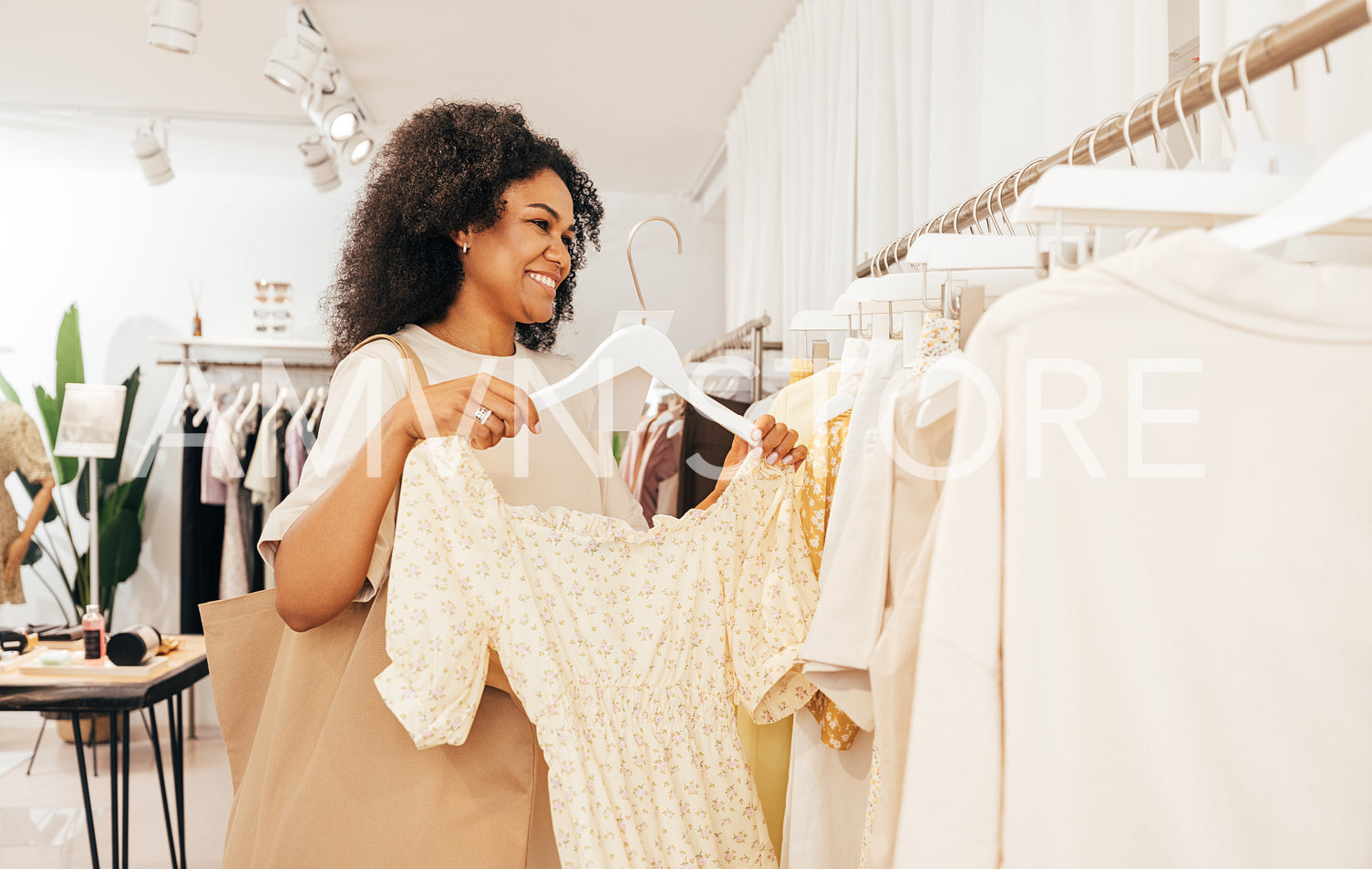 Stylish woman with shopping bag holding hanger with dress in a b