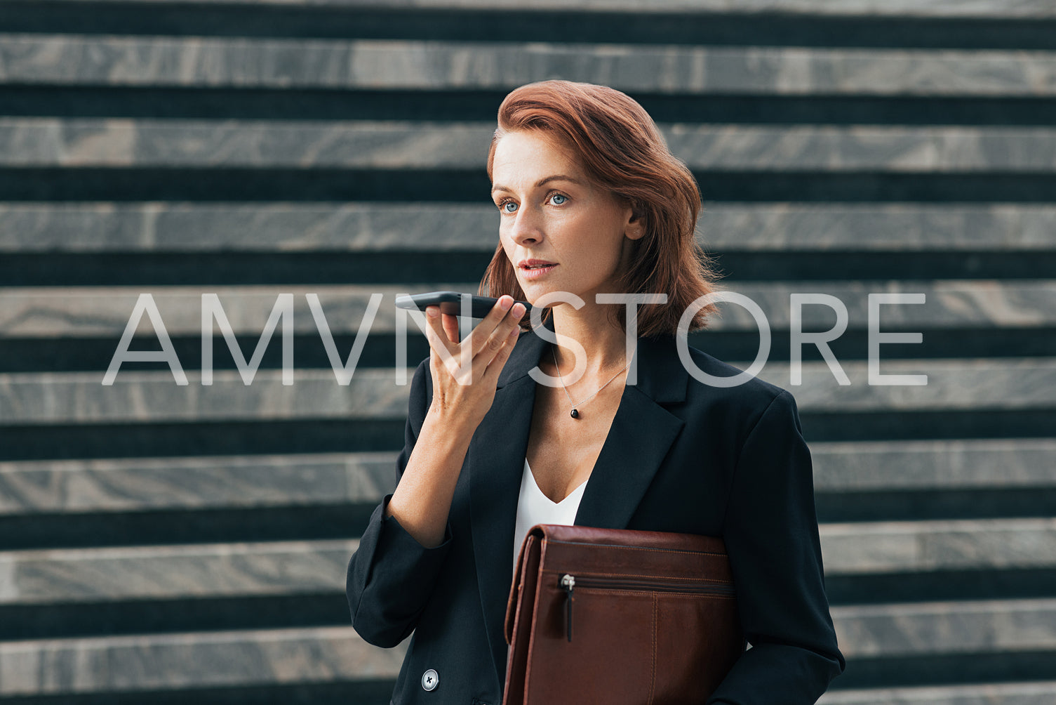 Confident business woman recording voice message while standing outdoors