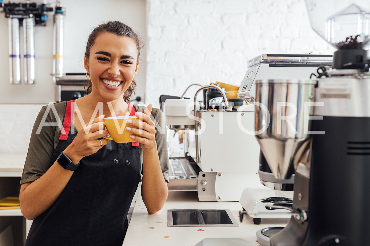 Laughing barista holding a mug. Smiling waitress taking a break in the cafeteria.