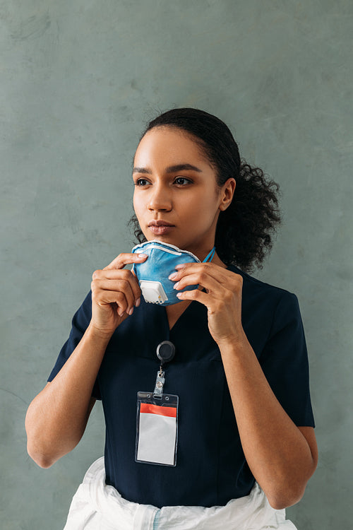 Portrait of female medical worker wearing a respirator at wall and looking away