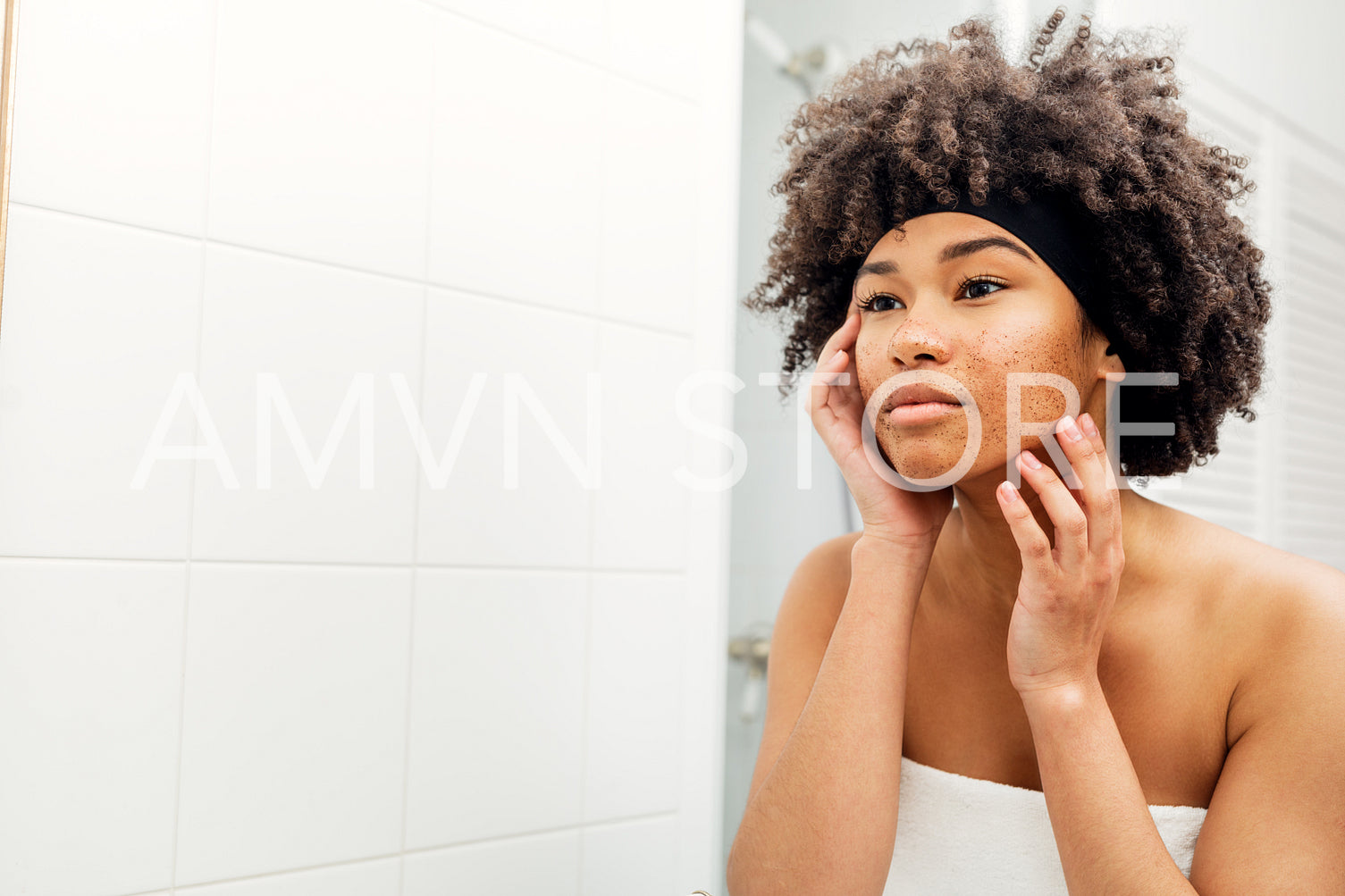 Portrait of a woman cleaning her face with the facial scrub	