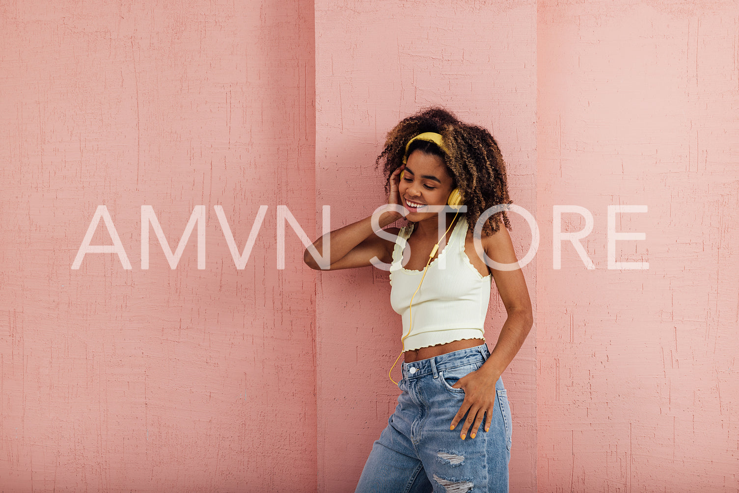 Young stylish woman wearing yellow headphones leaning a pink wal