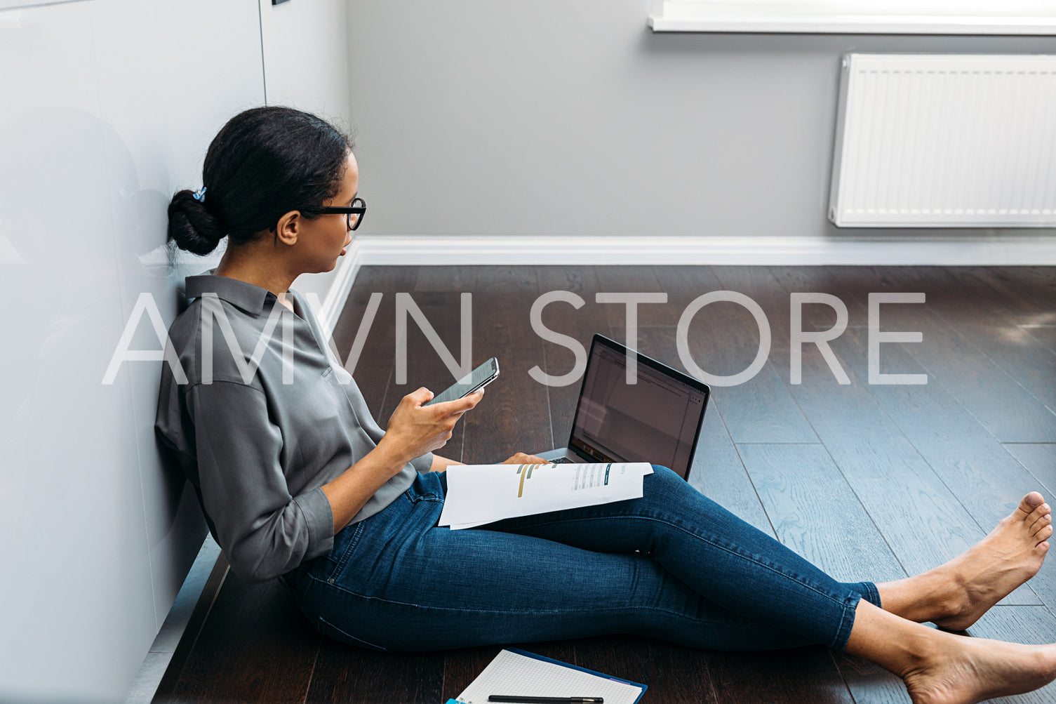 Side view of an entrepreneur woman holding a smartphone and looking on a laptop screen	