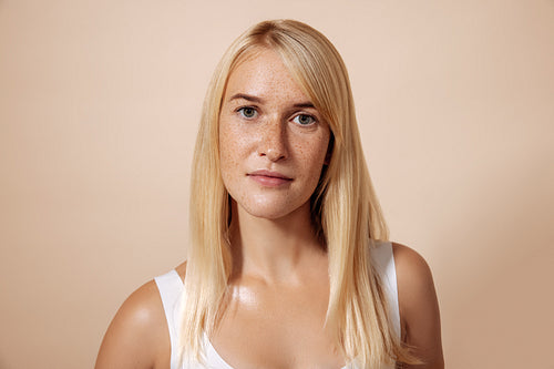 Portrait of young blond woman with freckles standing in a studio