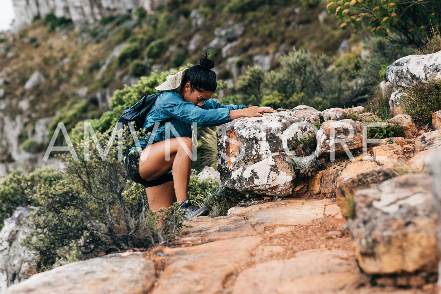 Side view of woman hiker grabs a big rock to helps her climbing up