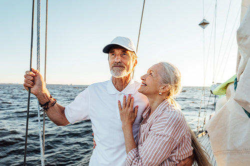 Smiling mature woman looking at his husband while standing at sail on a yacht