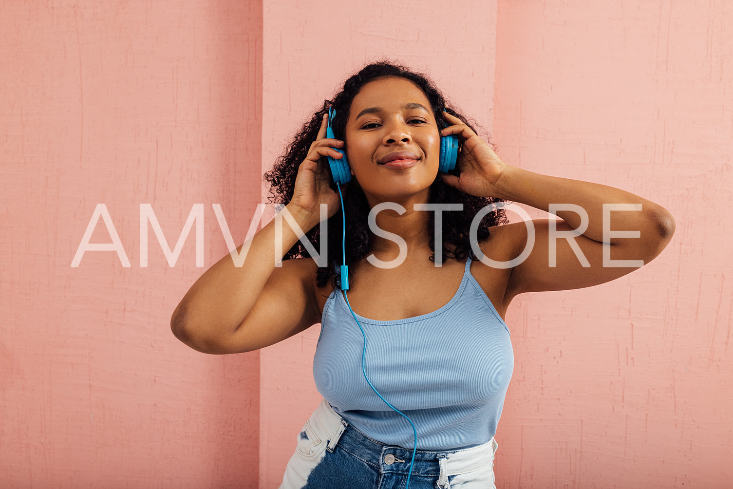 Smiling woman listening to music wearing blue headphones