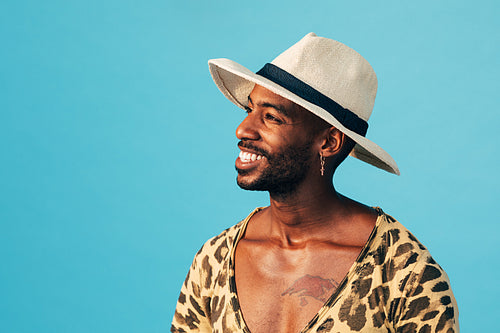 Happy man in white hat standing against blue background looking away