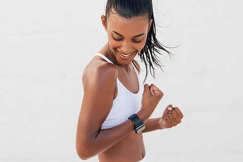 Smiling fit woman showing her biceps. Young happy female looking at her muscles on a hand.